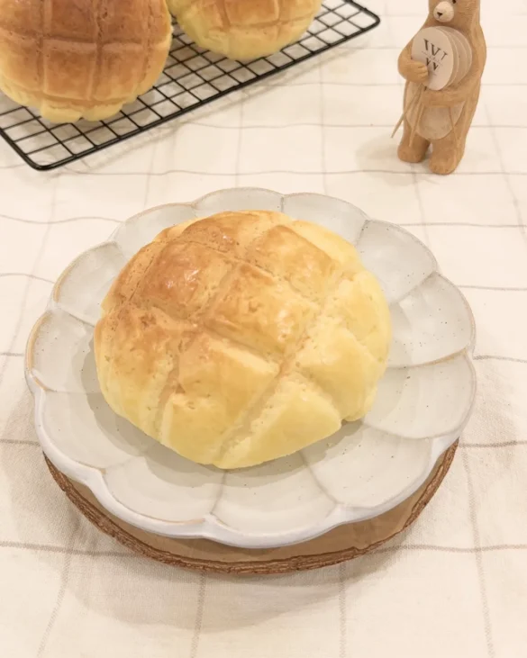 剛出爐的菠蘿麵包放在花瓣盤上，表面格紋清晰金黃